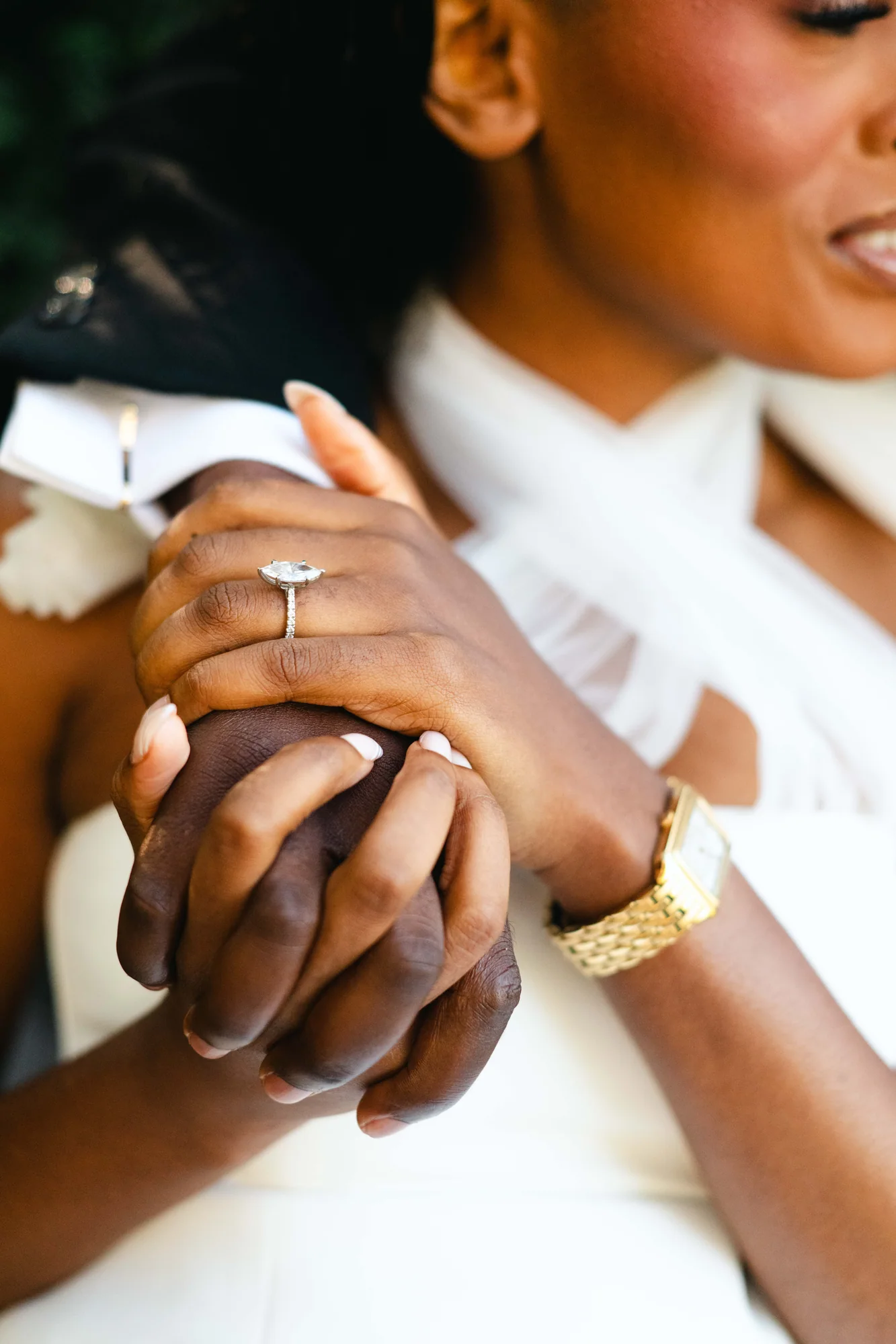 A close-up of their hands and engagement ring