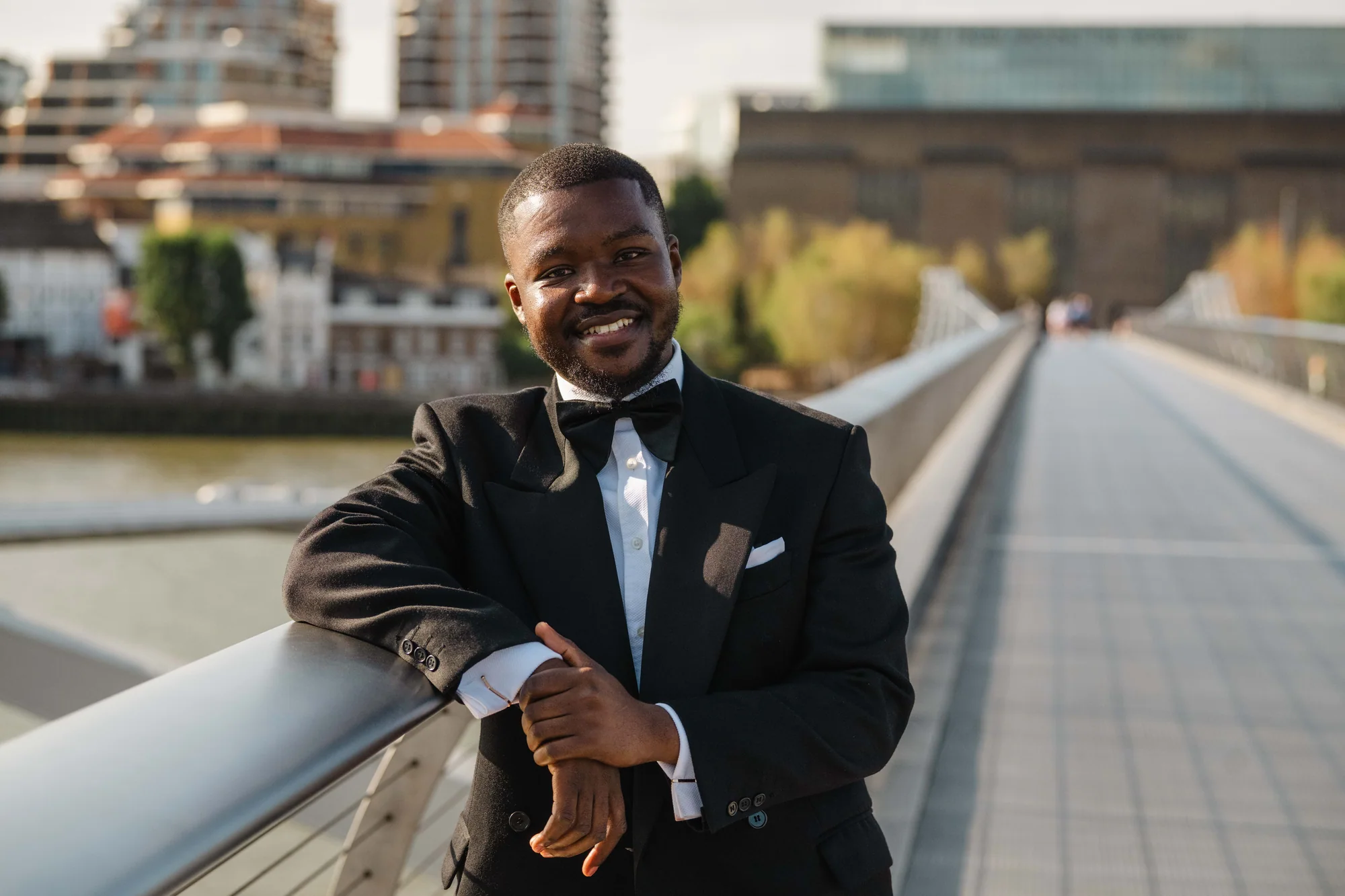 Kennedy smiling beside the railing on Millennium Bridge