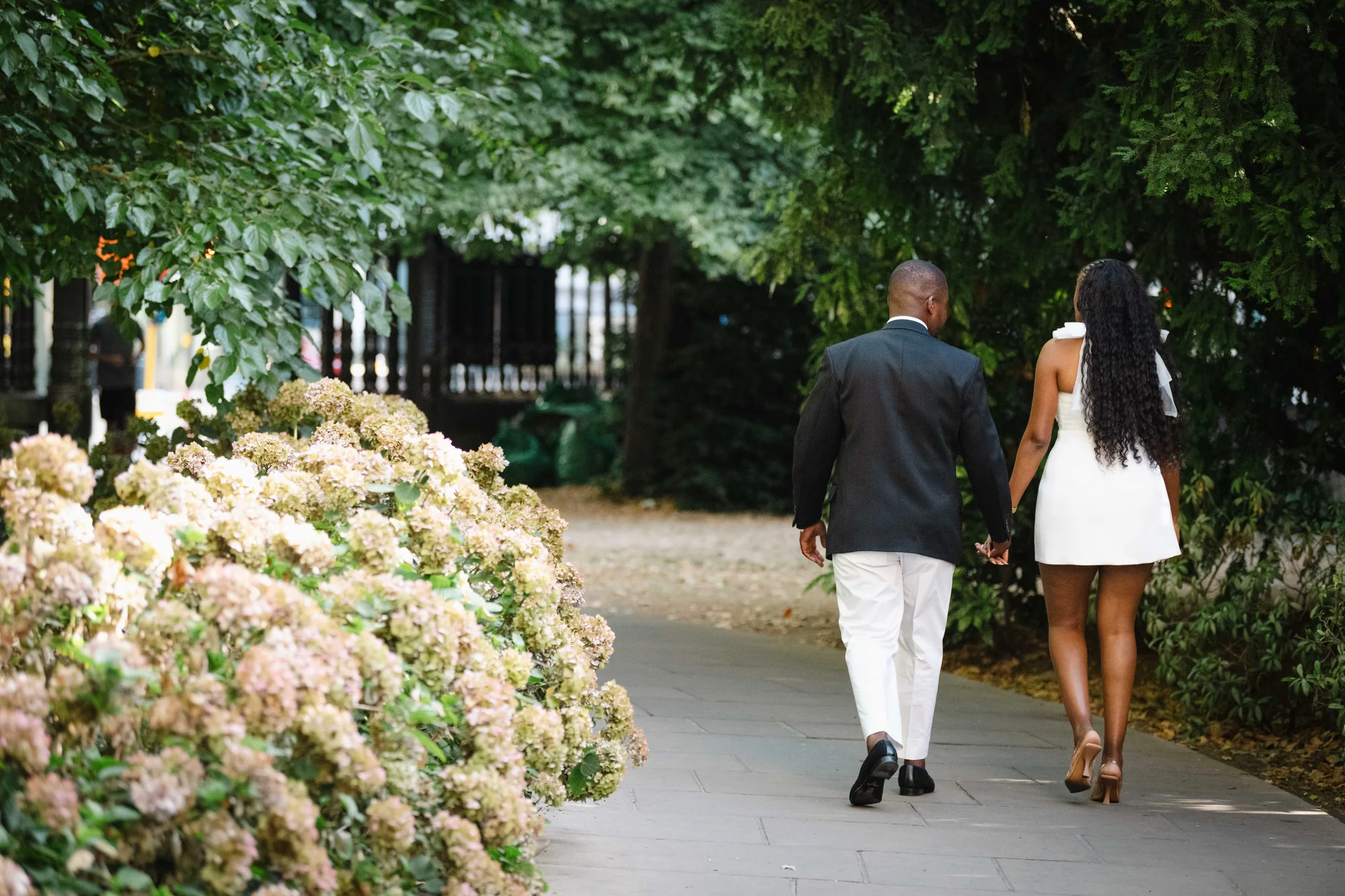 Kennedy and Didimalang walking hand in hand through a leafy garden